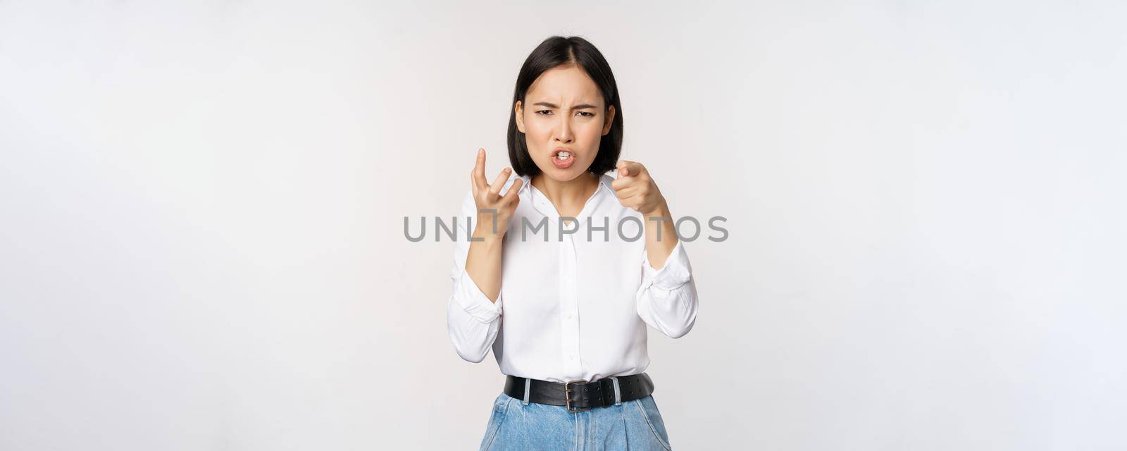 Image of angry pissed off woman shaking from anger, clench hands and grimacing furious, annoyed and outrated, standing over white background.