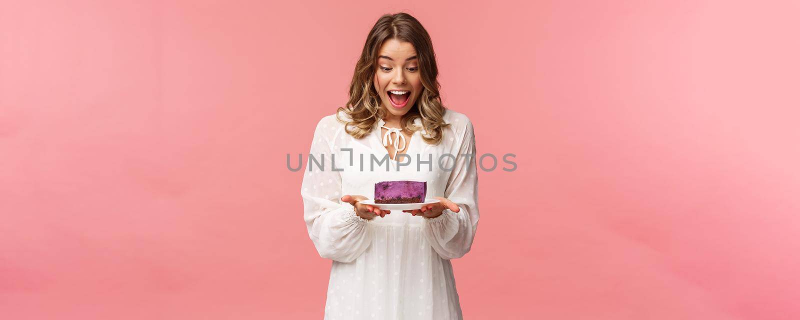 Holidays, spring and party concept. Portrait of happy and excited young blond girl decided start day with sweets, look amazed and cheerful and piece of delicious cake, cant wait to eat it.