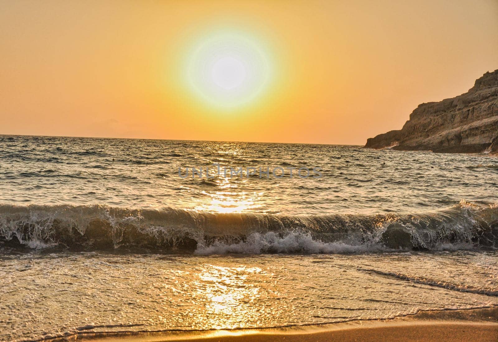 Sunset in Matala beach with caves on the rocks that were used as a roman cemetery and at the decade of 70's