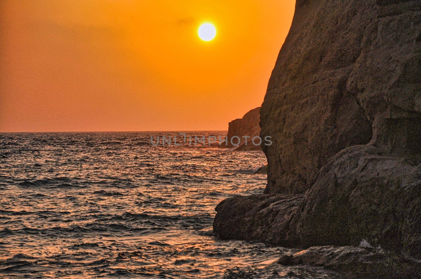 Sunset in Matala beach with caves on the rocks that were used as a roman cemetery and at the decade of 70's