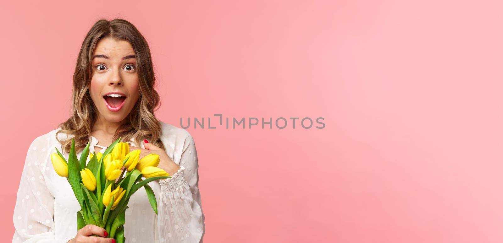 Spring, happiness and celebration concept. Close-up of surprised and wondered young blond girl in white dress, receive yellow tulips and pointing herself with disbelied and amazement, didnt expact by Benzoix