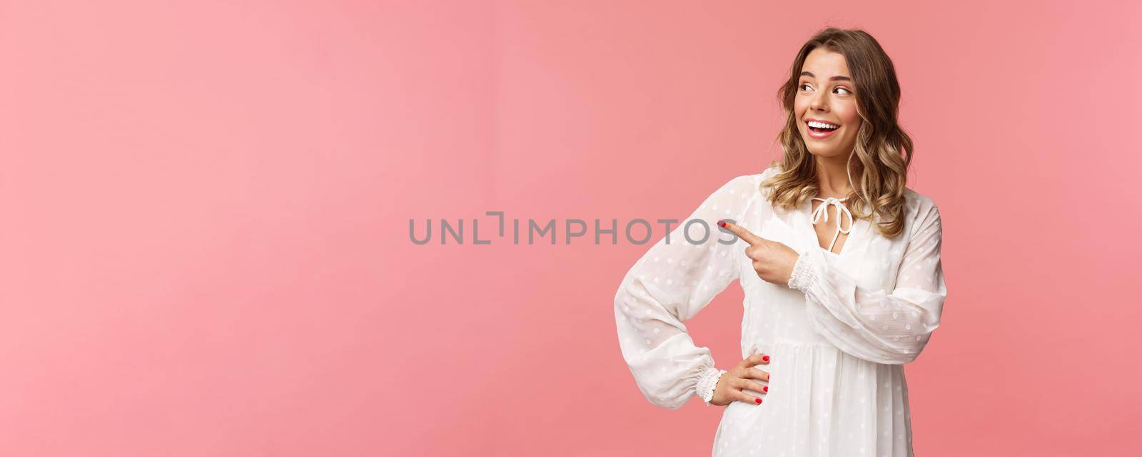 Curious upbeat beautiful blond woman enjoying summer feeling cheerful, pointing looking left with interested, enthusiastic expression, wear cute white dress, standing pink background by Benzoix