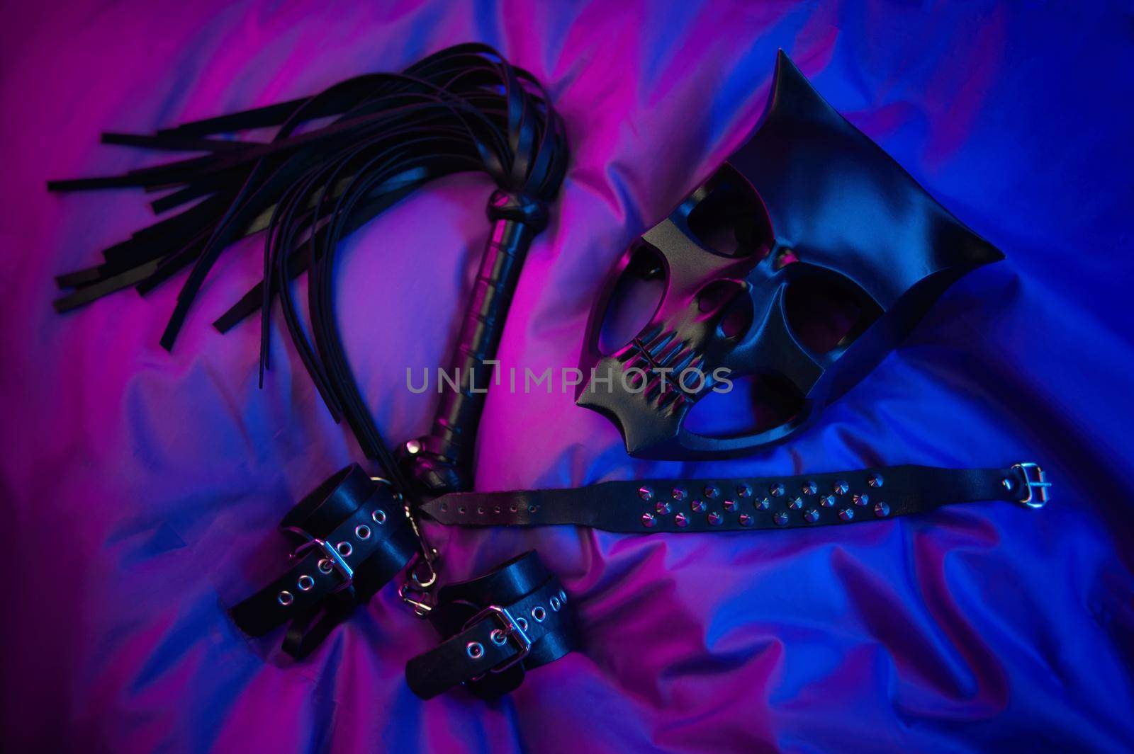 bdsm mask and leather accessories for bdsm games in neon light by Rotozey