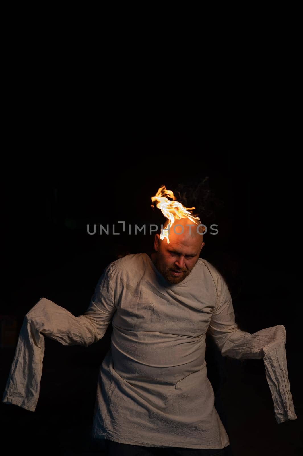 Bald man in a straitjacket with a burning head on a dark background. by mrwed54