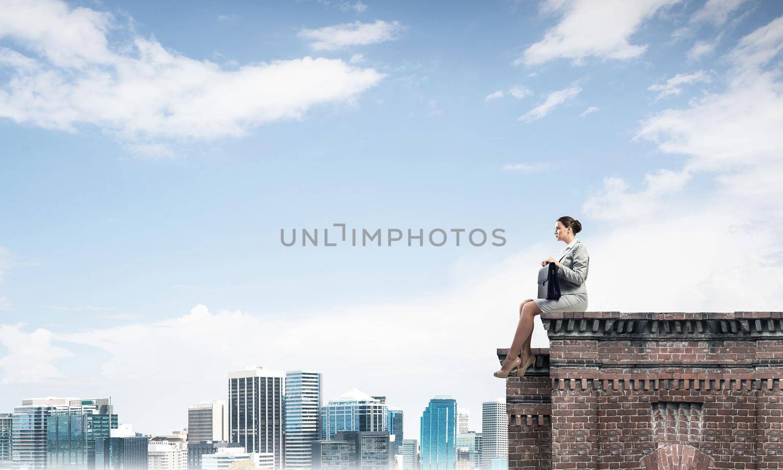Businesswoman or accountant on brick roof against modern city scape by adam121
