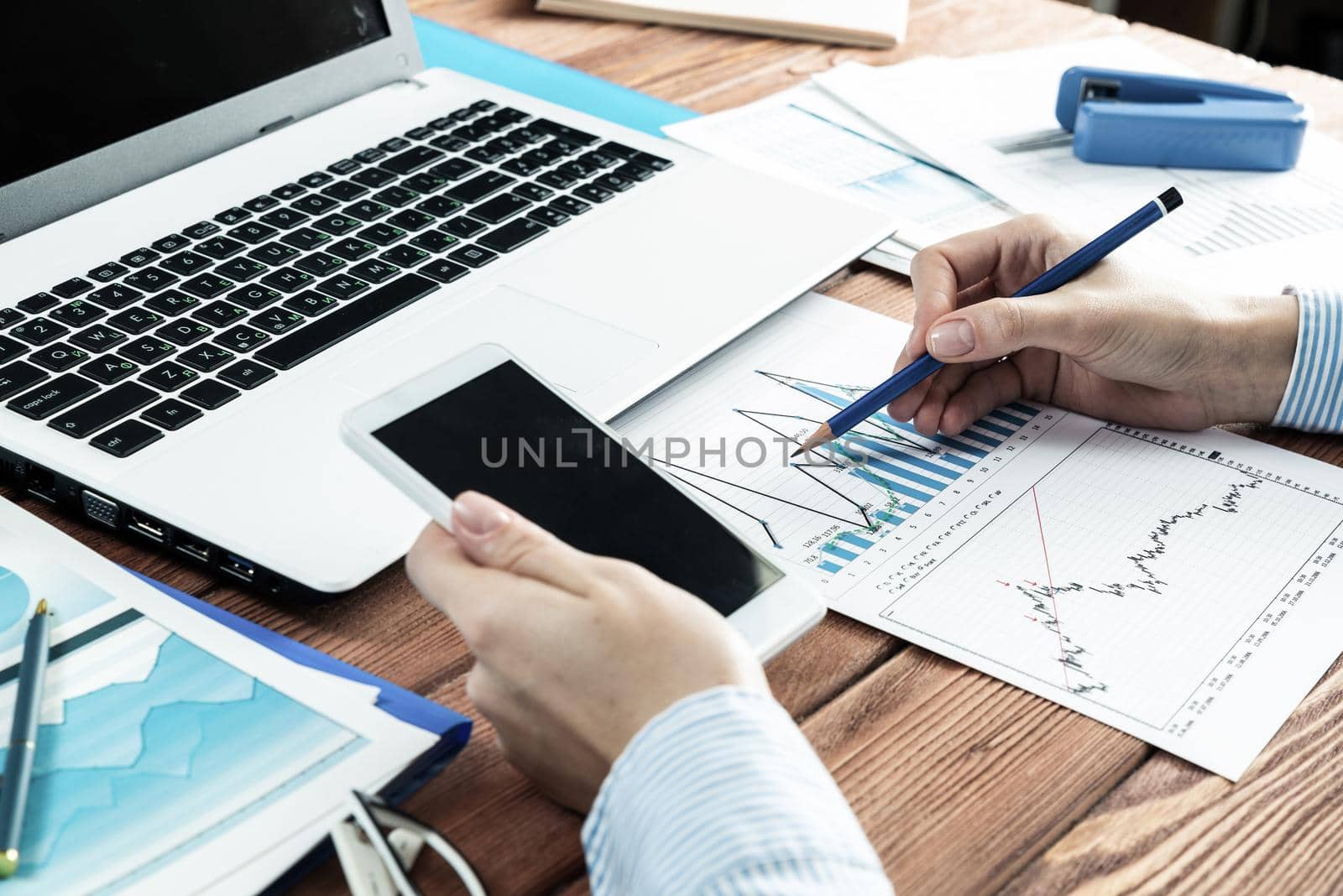 close-up, female hands with phone and chart document. Business woman working at the table in office