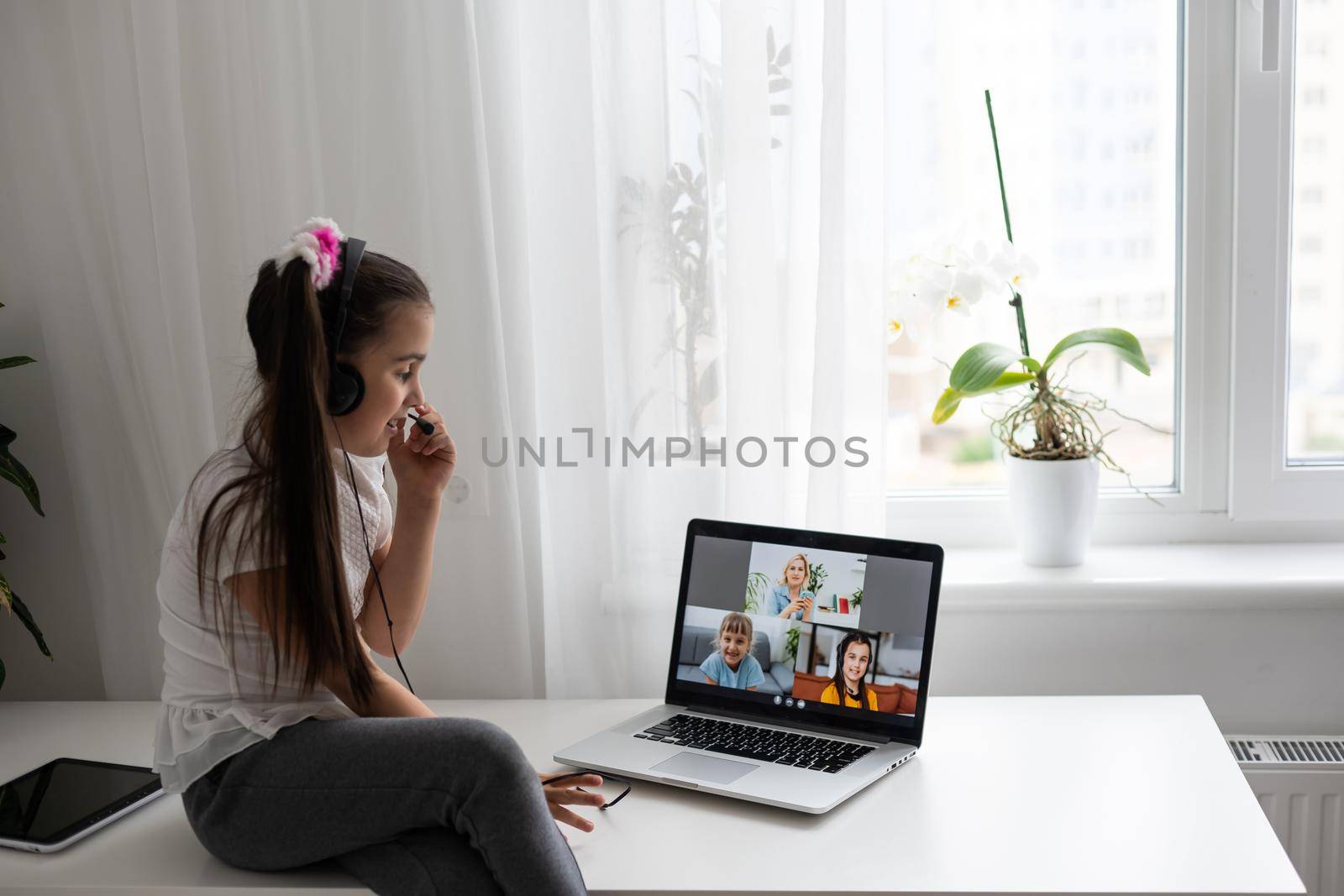 Little girl studying online using her laptop at home.
