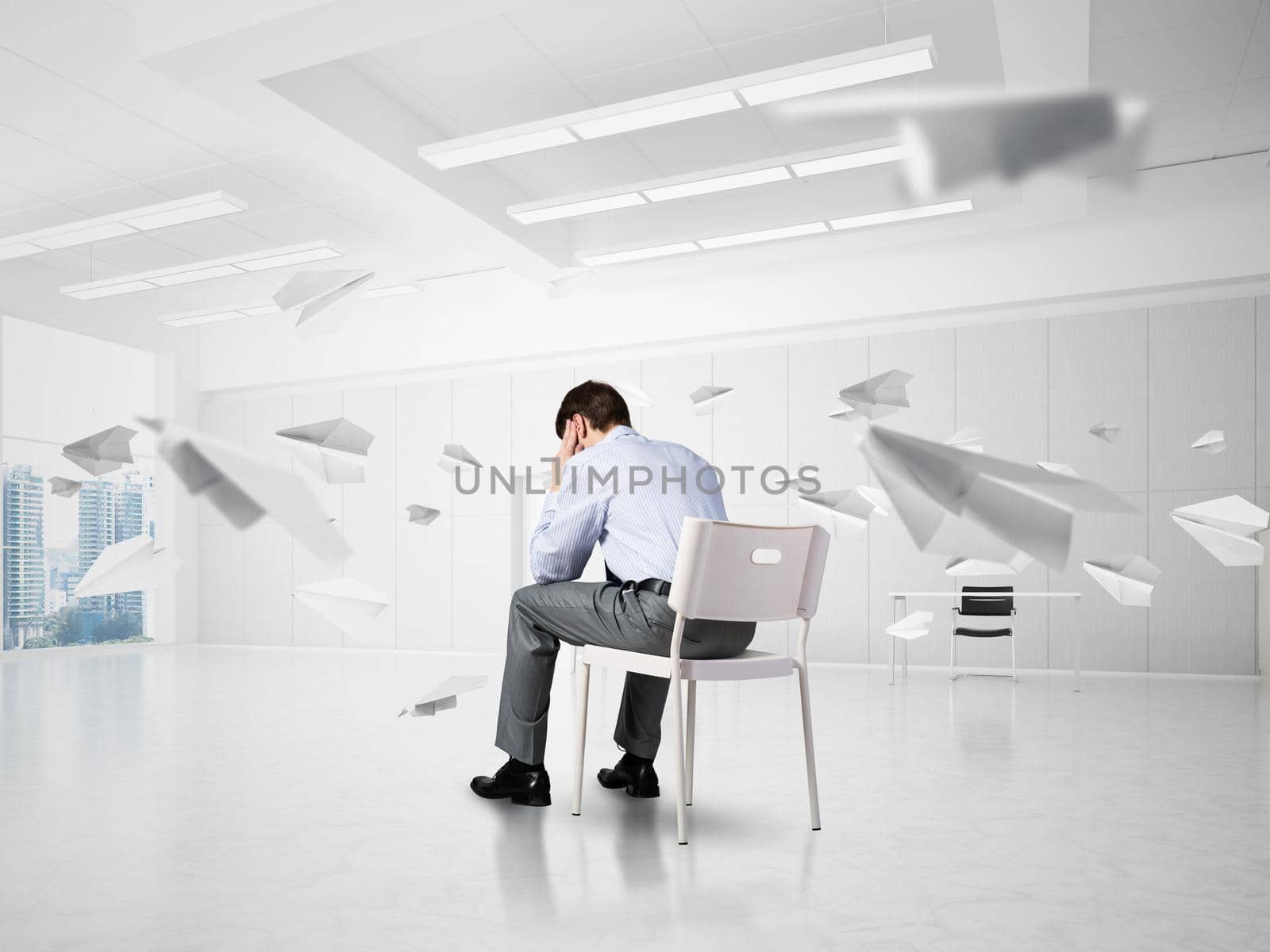 young businessman sitting on a chair with his head in his hands