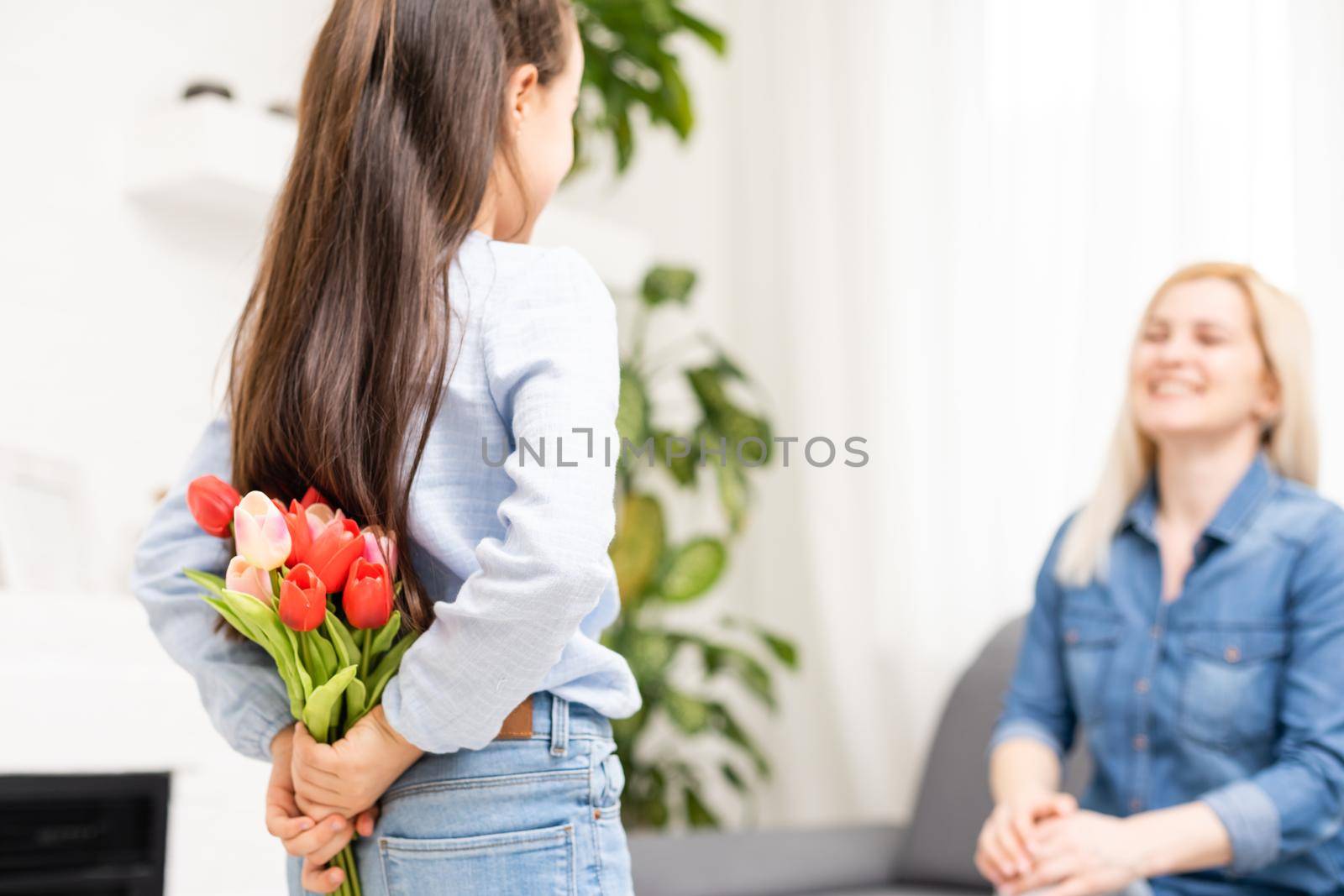 child daughter congratulates mother and gives a bouquet of flowers tulips.