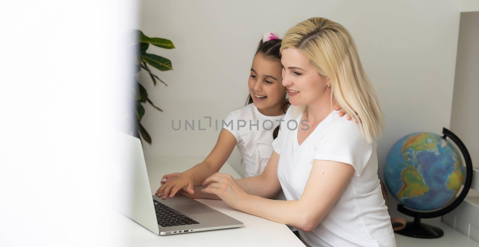Online education of children. Mother and daughter of preschool watching a video lesson call chat at home