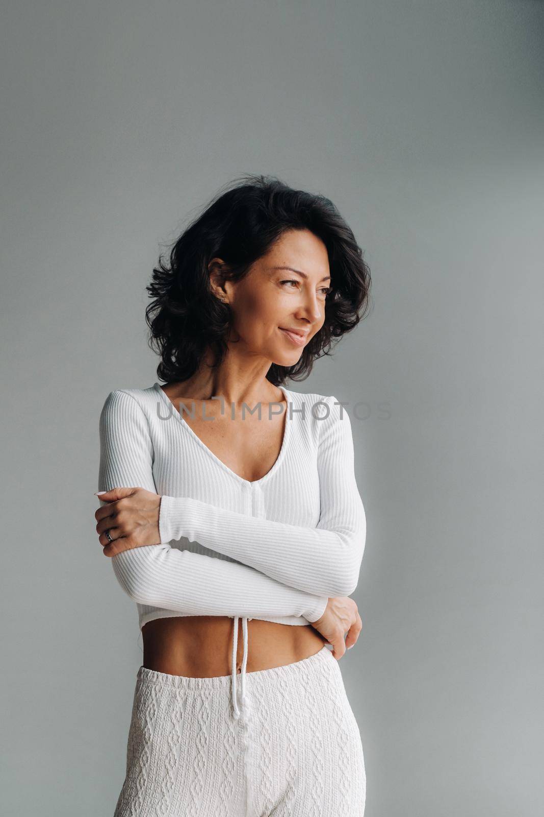 Portrait of a cheerful smiling woman in white sportswear, highlighted on a gray background by Lobachad