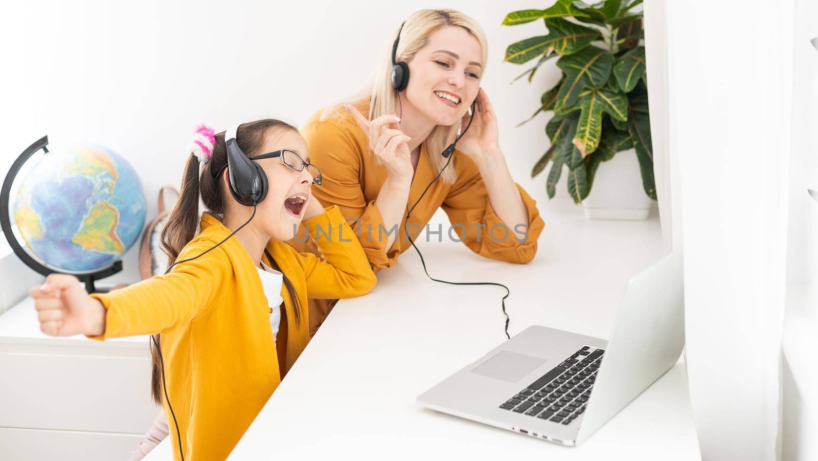 Mother and her girl listening to music on laptop. They sitting in living room. Natural light ambient. by Andelov13