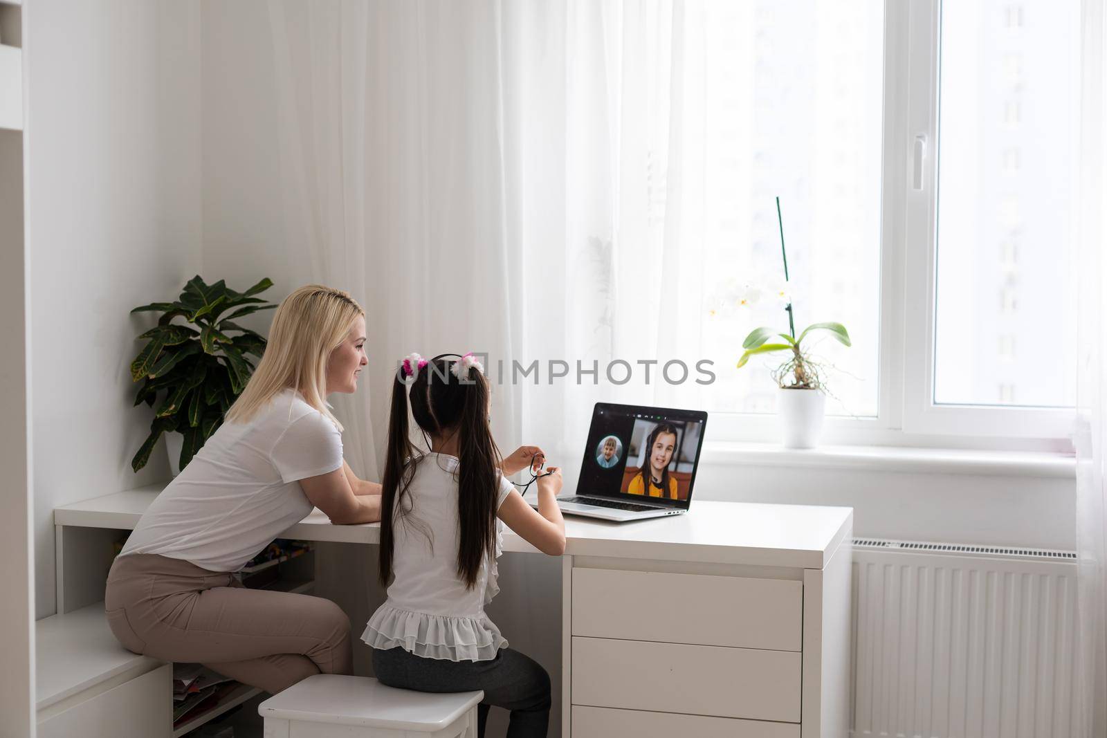 Private lesson. Attentive young woman tutor teacher help little girl pupil with studying math language correct mistakes explain learning material. Smiling mother assist small daughter with home task.