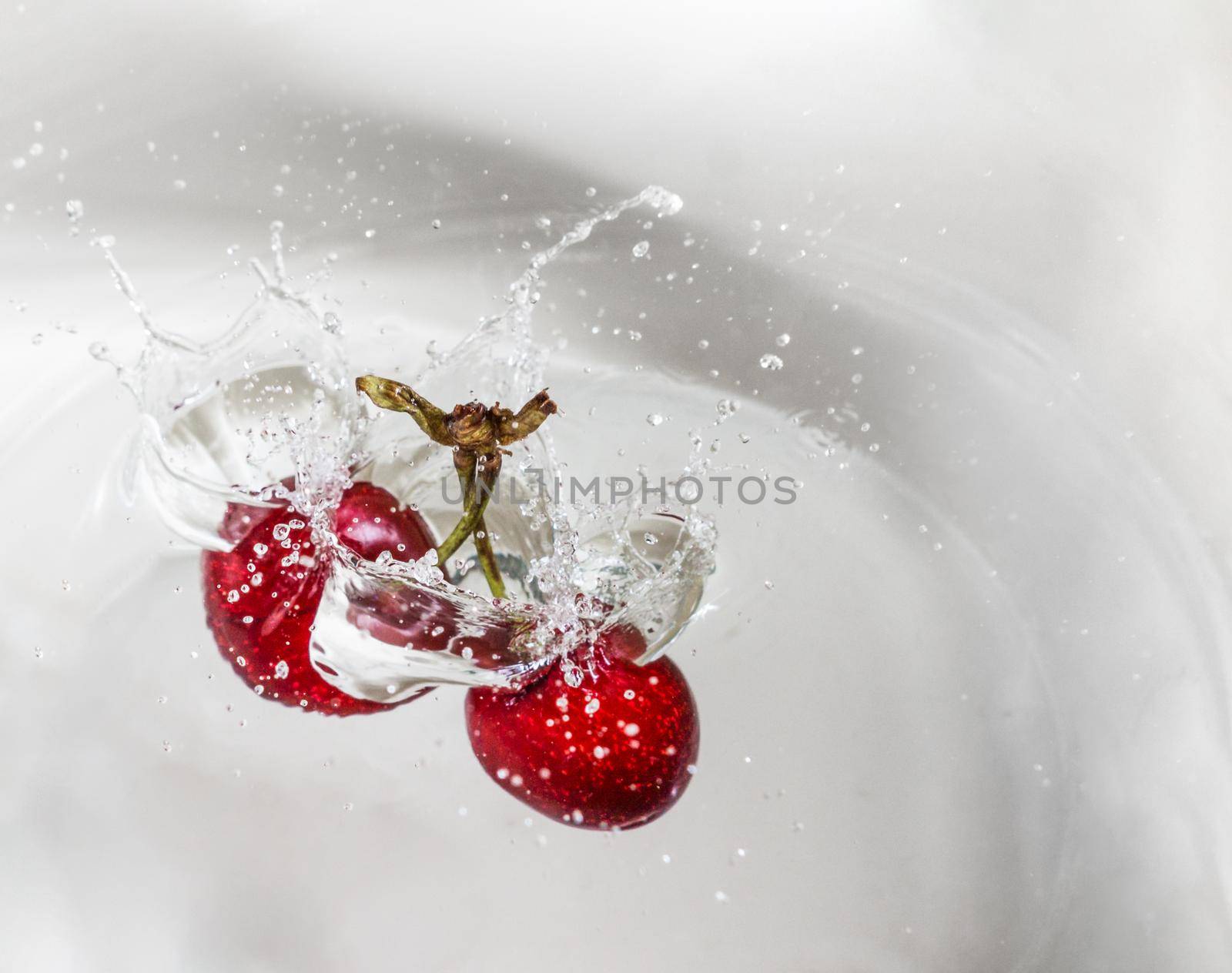 two cherries at high speed falling into the water