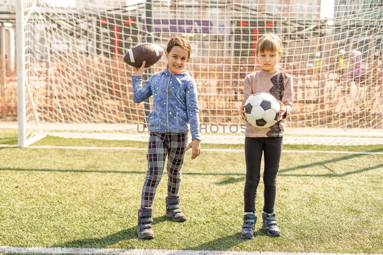 Little football team: toddler girls with soccer ball at football field. by Andelov13
