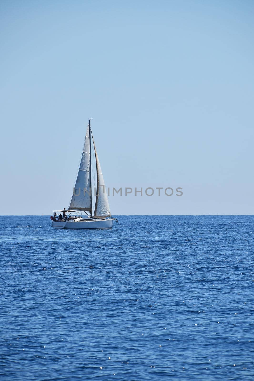 Tranquil seascape with calm sea water ripples and waves and sail yacht under clear day blue sky, high angle view