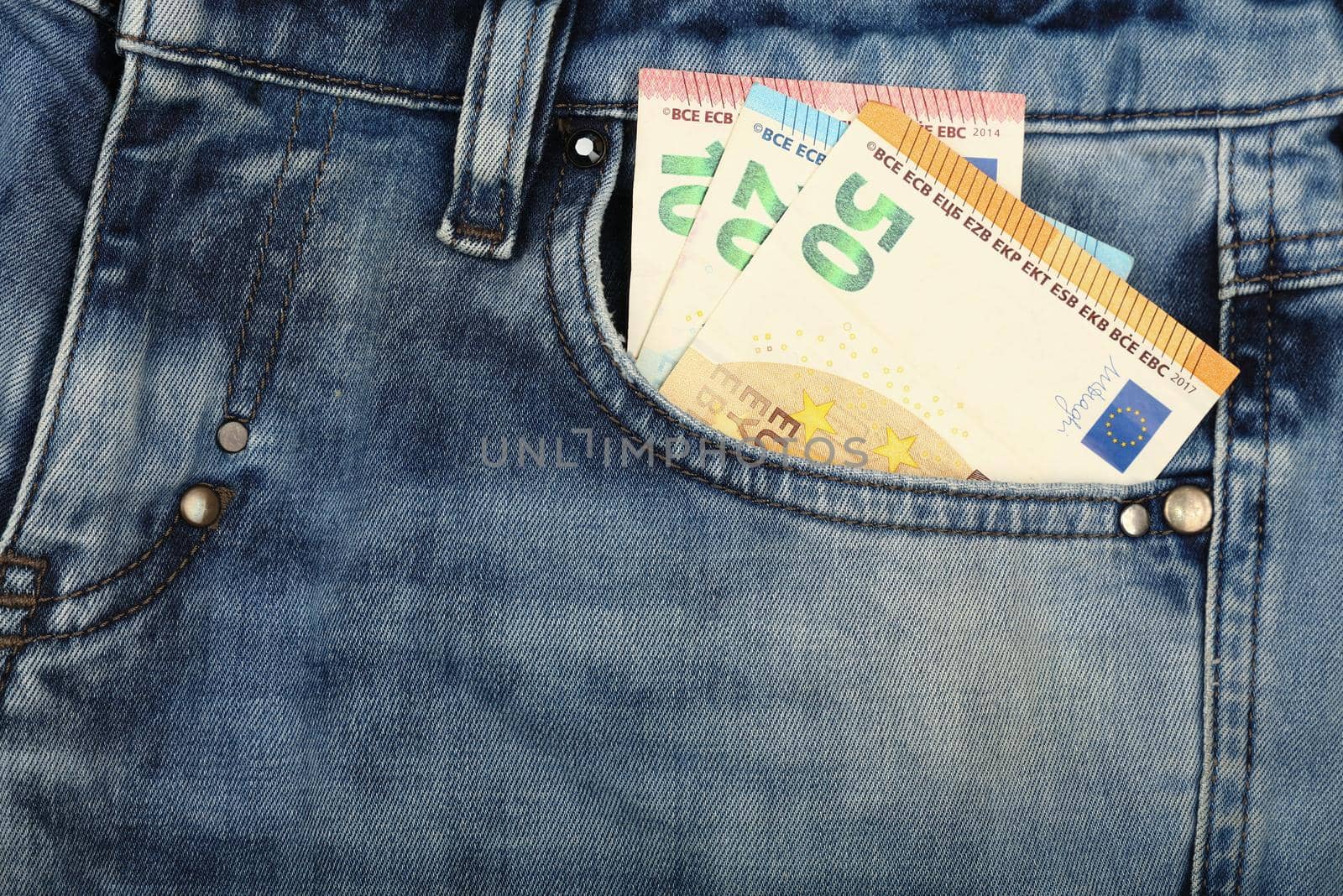 Close up several Euro paper currency banknotes in jeans front pocket, low angle view