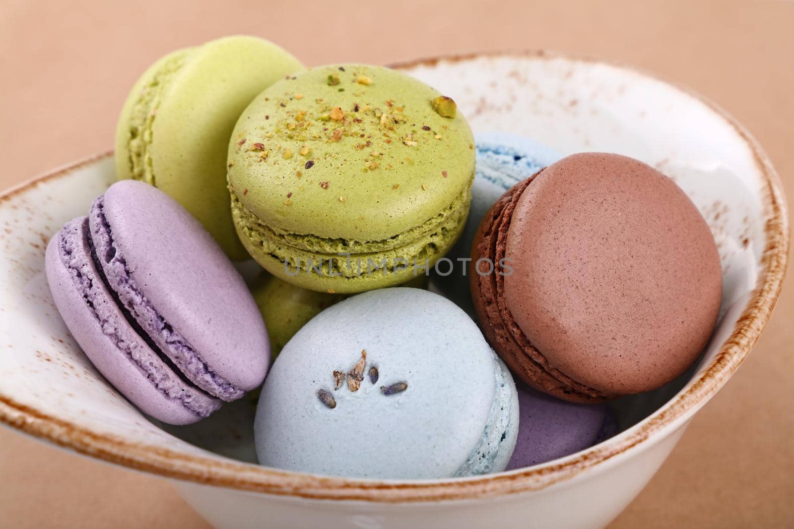 Close up several French macaroon cookies served in rustic porcelain bowl, high angle view