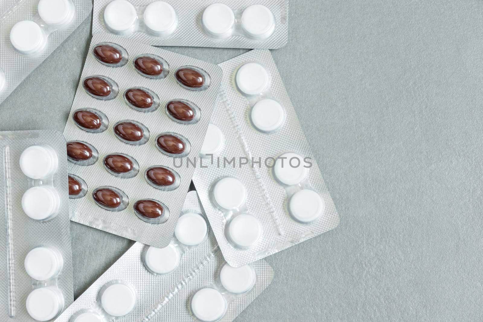 image from above blister packs full of white and red medicine tablets on gray background