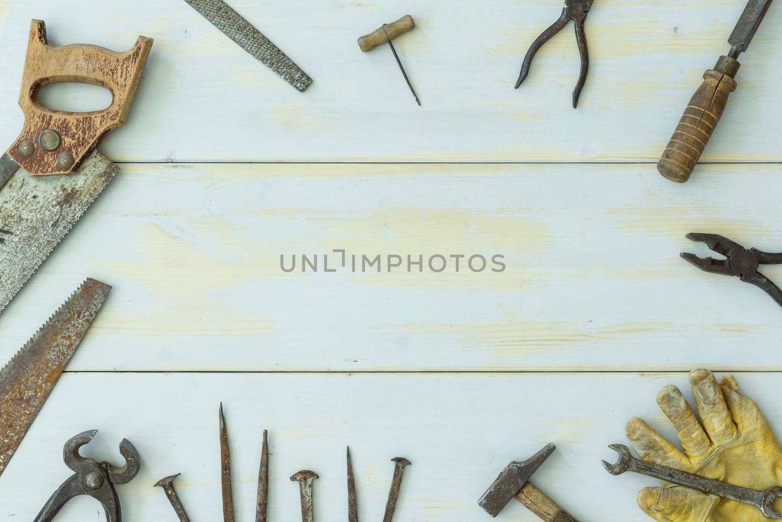 image from above of old tools on light wooden background scattered around image with negative space in center with natural light