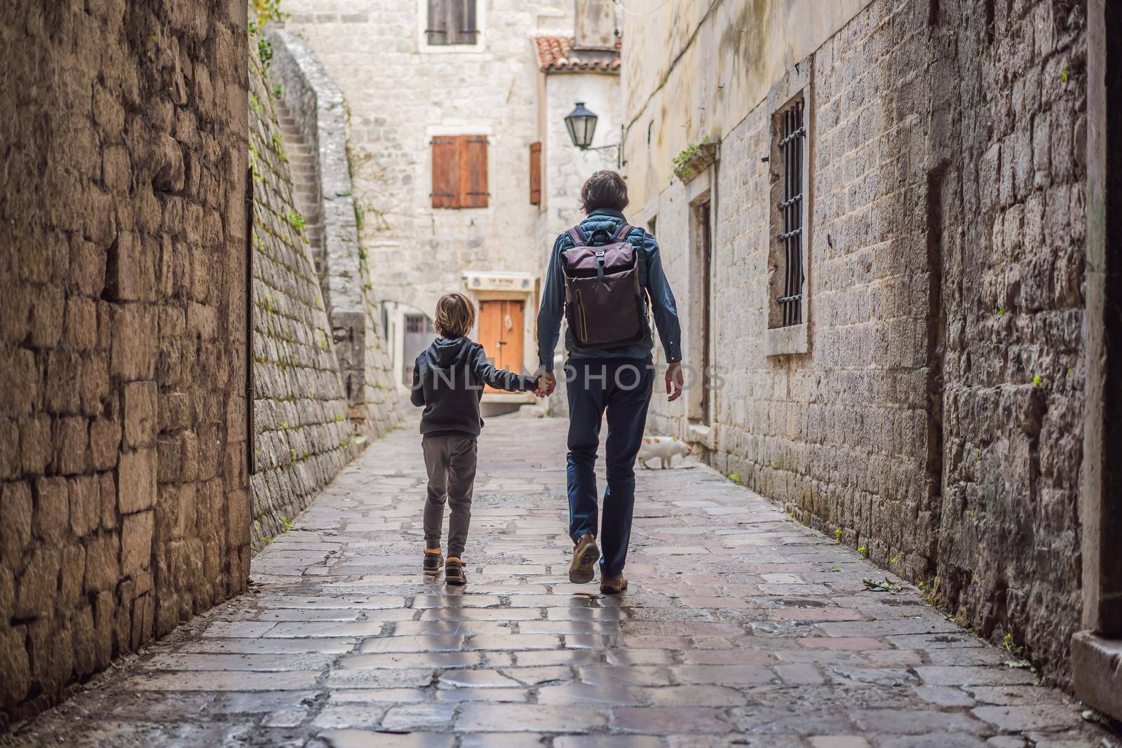 Dad and son travelers enjoying Colorful street in Old town of Kotor on a sunny day, Montenegro. Travel to Montenegro concept by galitskaya