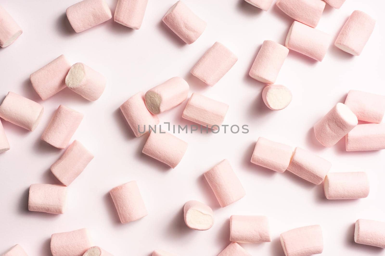 pink and white marshmallows randomly distributed on white background with soft side light