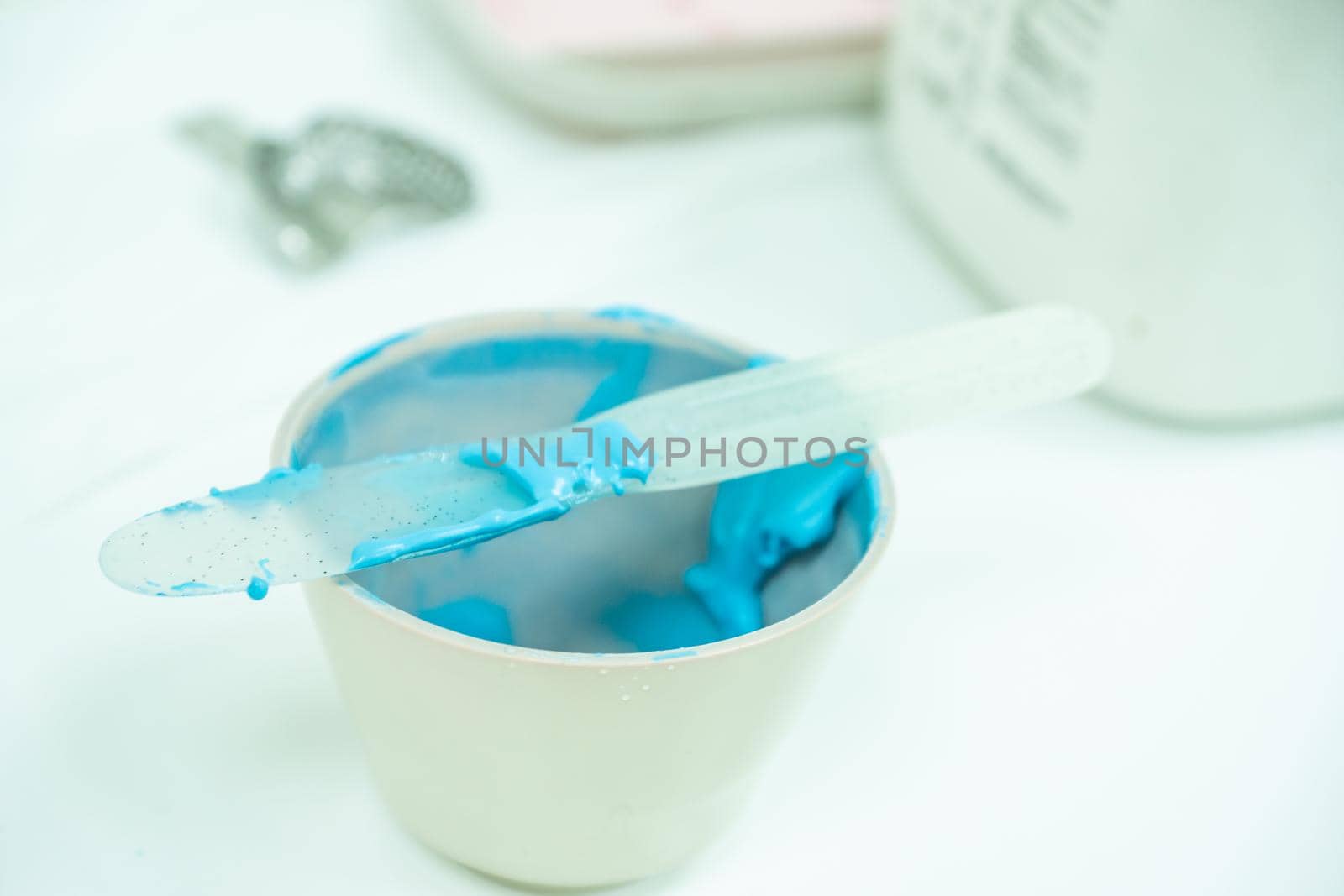 white bowl with blue alginate paste for dental impressions with plastic trowel for mixing