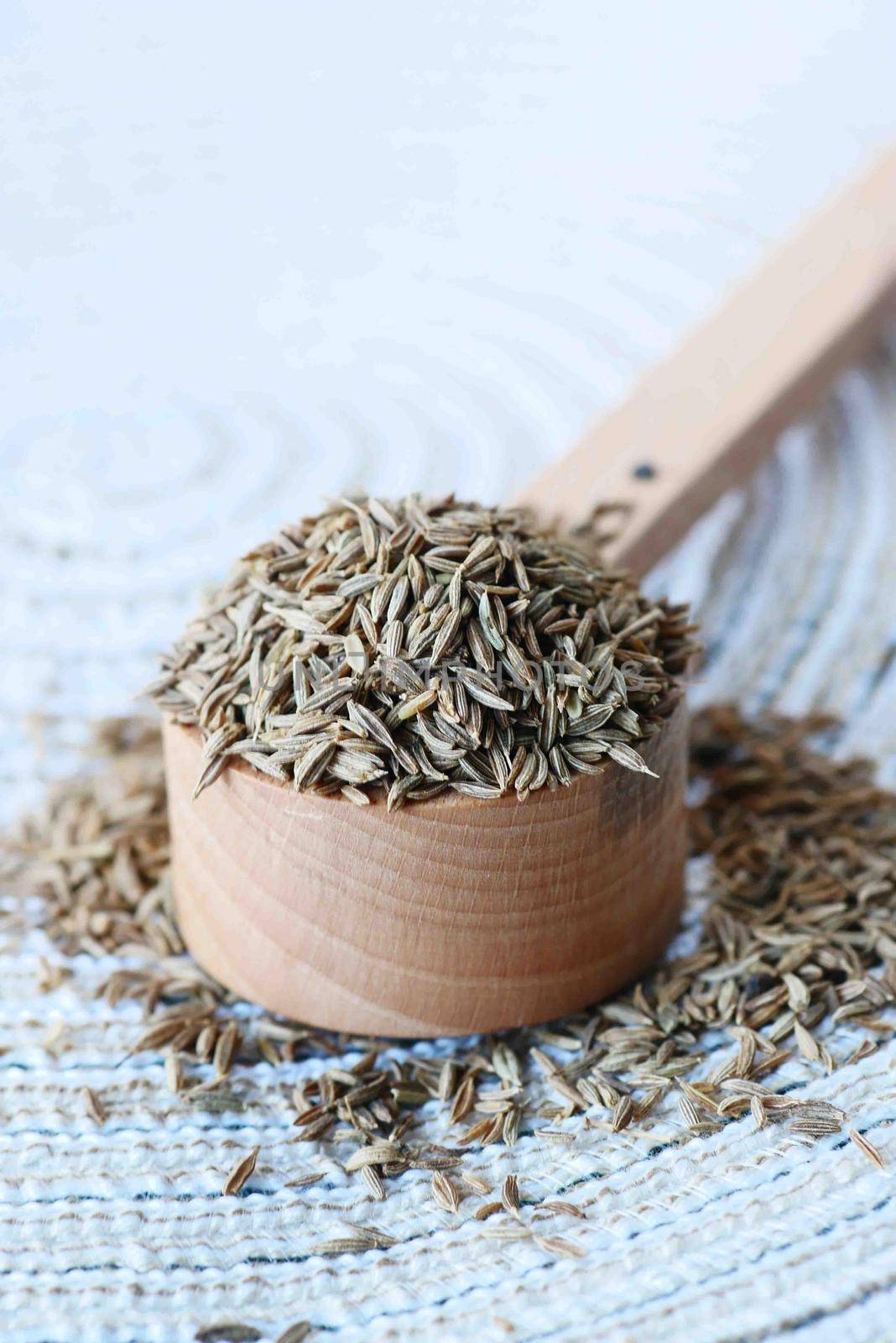 cumin seeds on spoon on table .