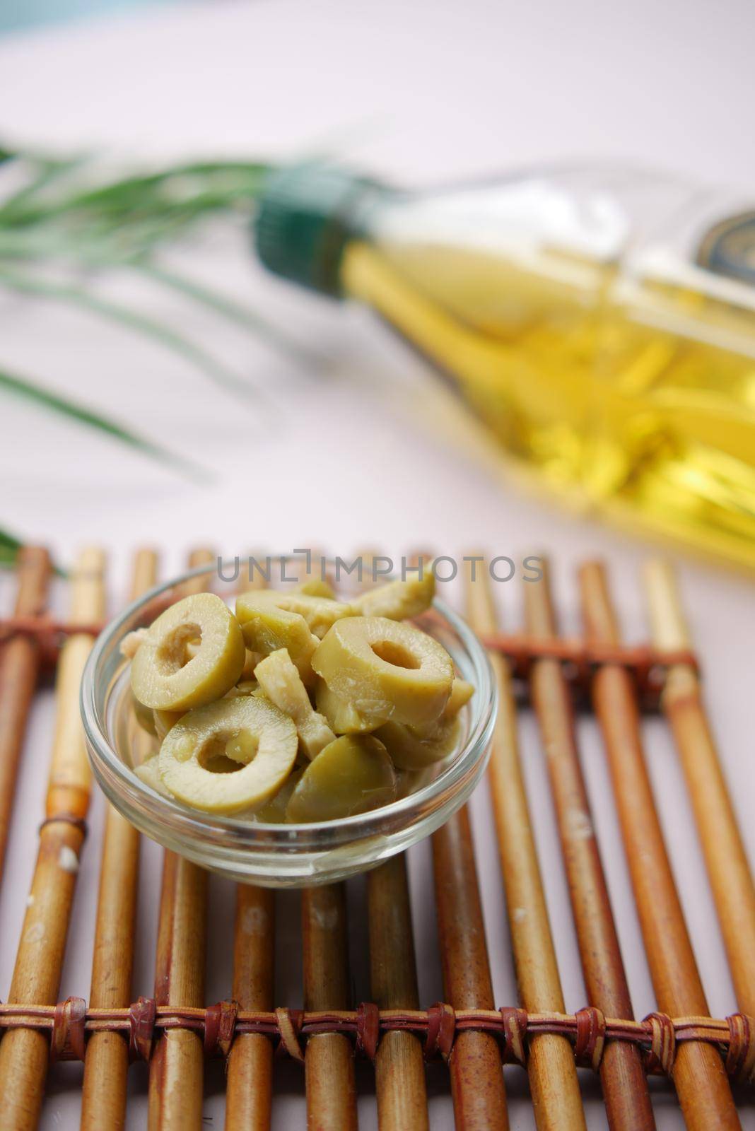 bottle of olive oil and fresh olive in a container on table . by towfiq007