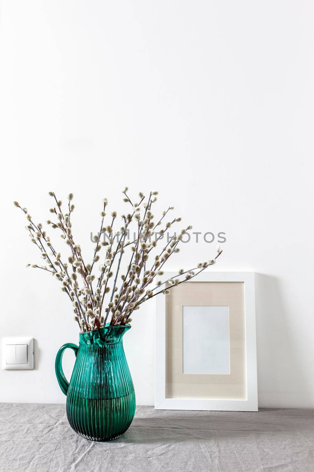 Blank canvas frame mockup. Artwork in interior design. View of modern style interior with canvas for poster on wall. Living room, table with green pitcher with willow branches. minimalism concept by elenarostunova