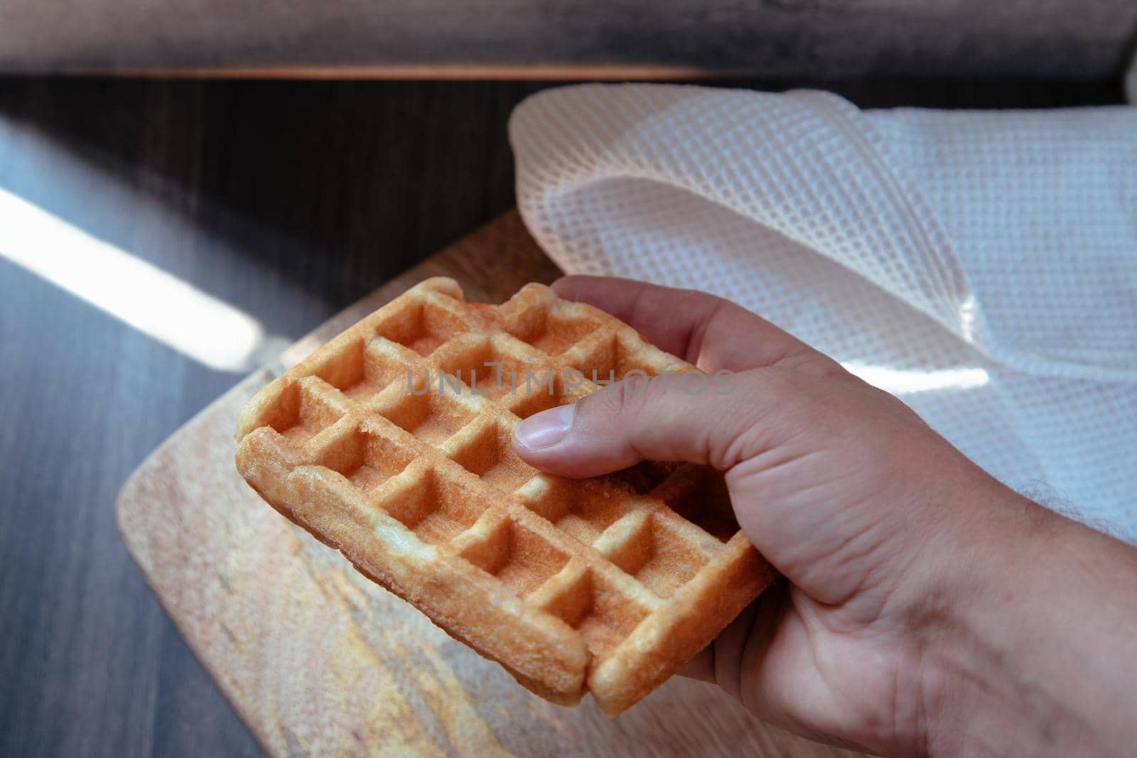 hand taking a waffle from the plate by jatmikaV