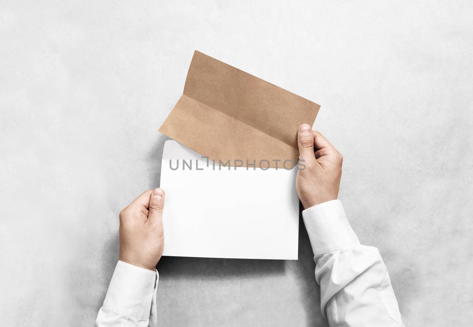 Hand holding white blank envelope and folded craft leaflet mockup by jatmikaV