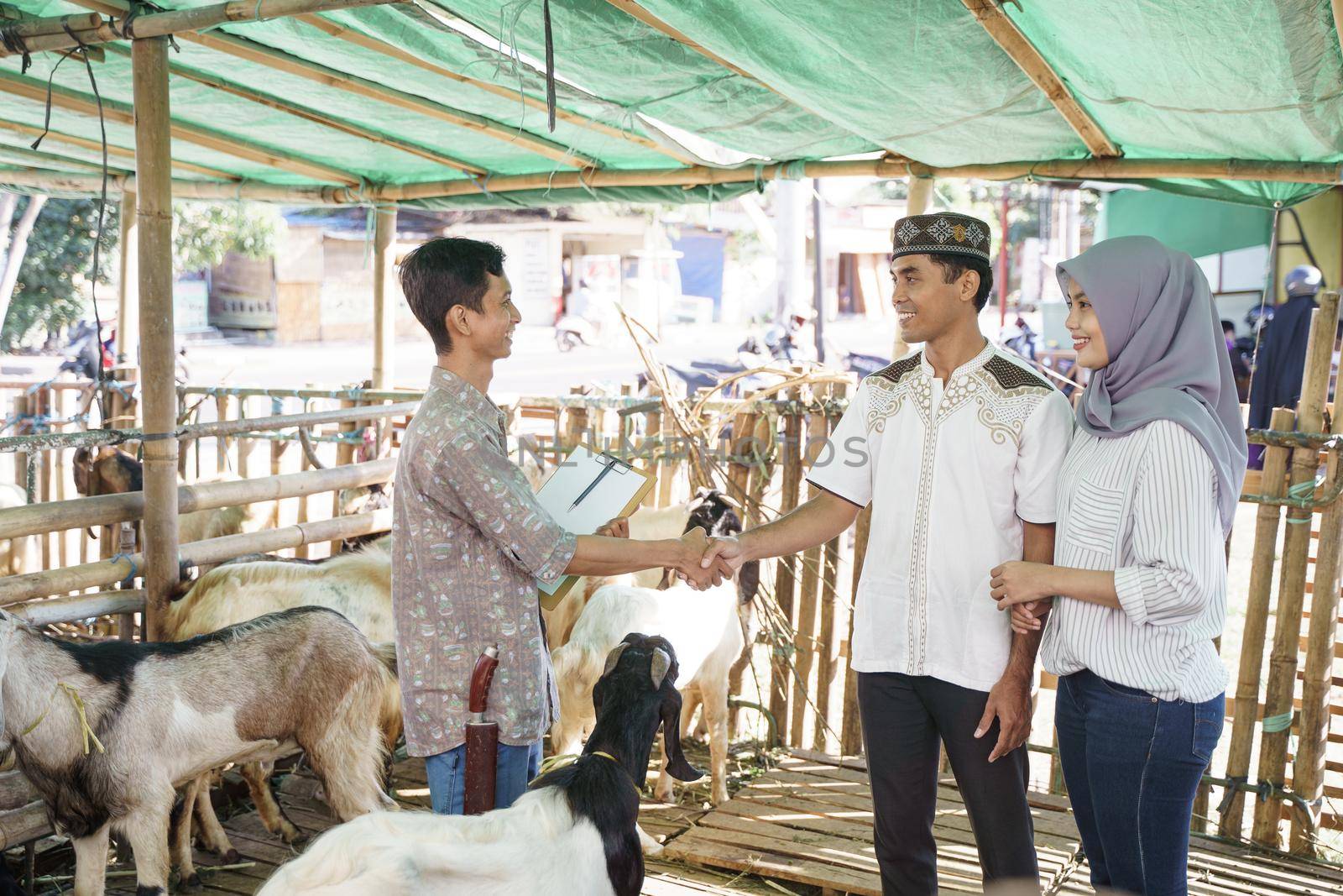 muslim people shake hand with farmer after buying a goat by jatmikaV