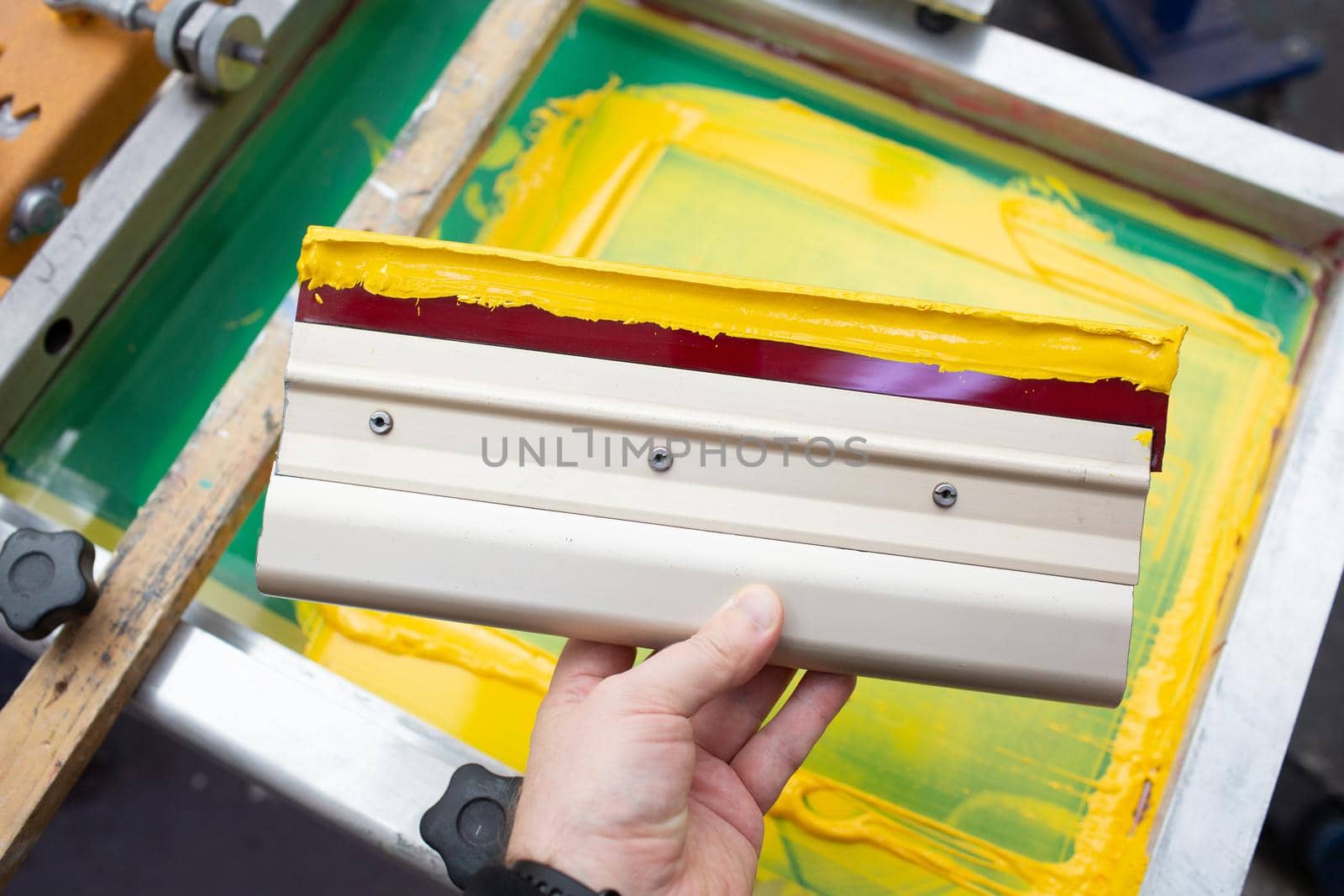 Squeegee for Serigraphy silk screen print process at clothes factory. Frame, squeegee and plastisol color paints by jatmikaV