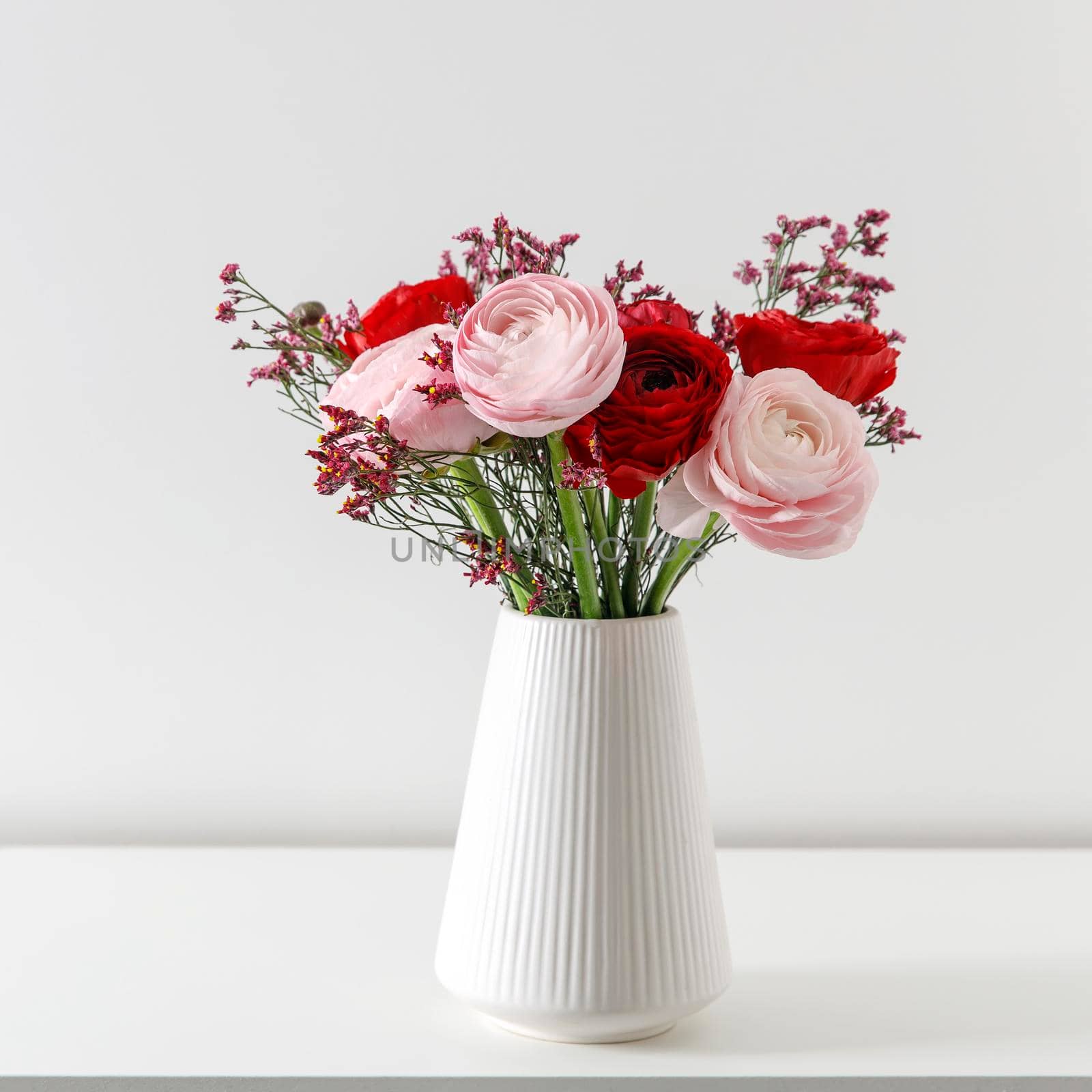 Persian pink buttercup in a beige wicker basket on a white background. Copy space