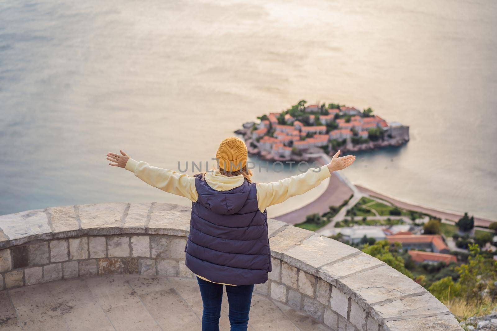 Woman tourist on background of beautiful view of the island of St. Stephen, Sveti Stefan on the Budva Riviera, Budva, Montenegro. Travel to Montenegro concept.