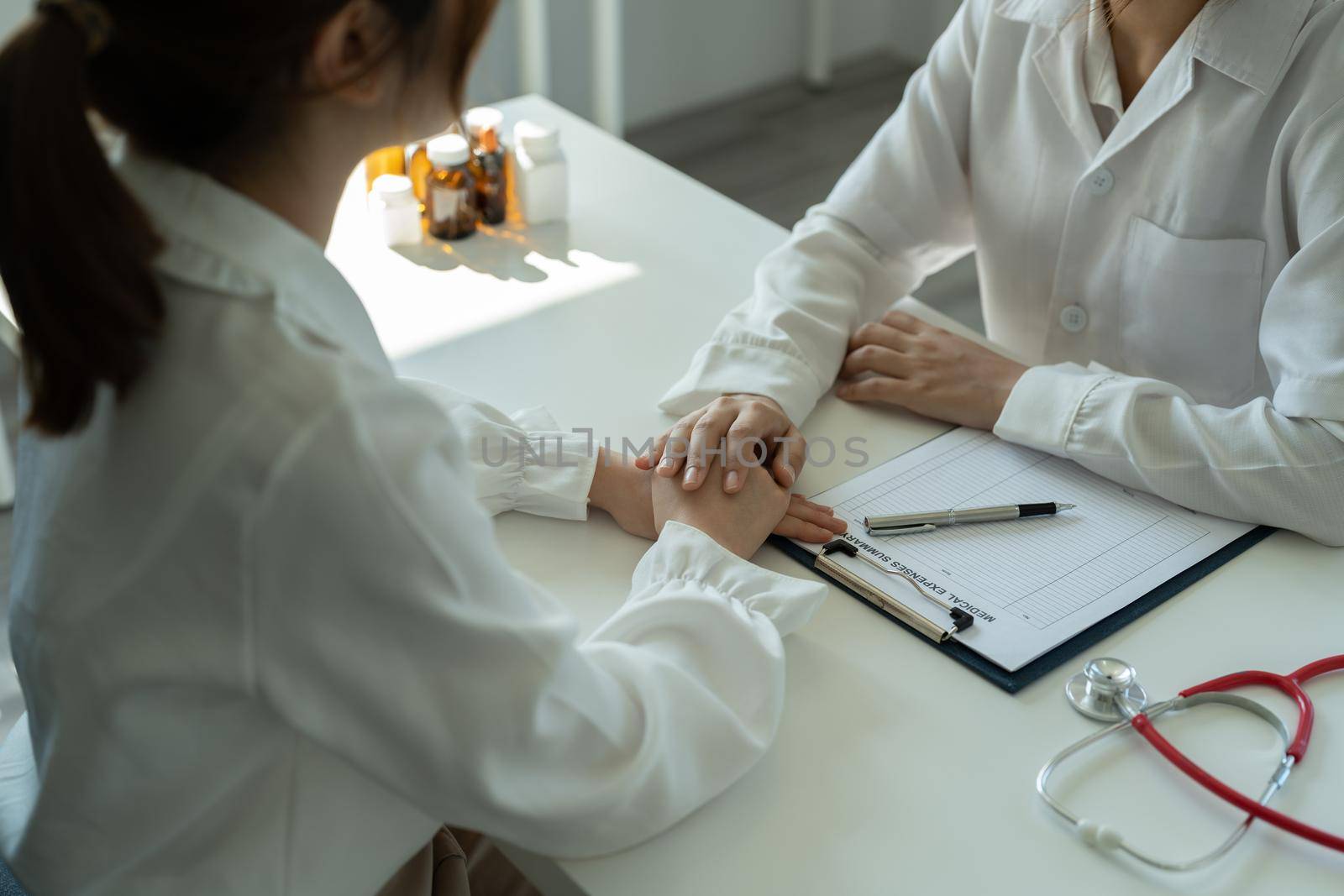 Asian female doctor in white medical uniform consult female patient in private hospital. woman therapist speak talk with woman client on consultation in clinic by nateemee