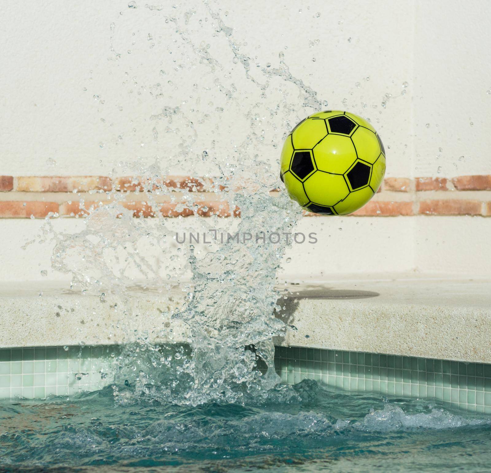 image of a yellow and black plastic ball popping out of the water at high speed with splashing water at high speed
