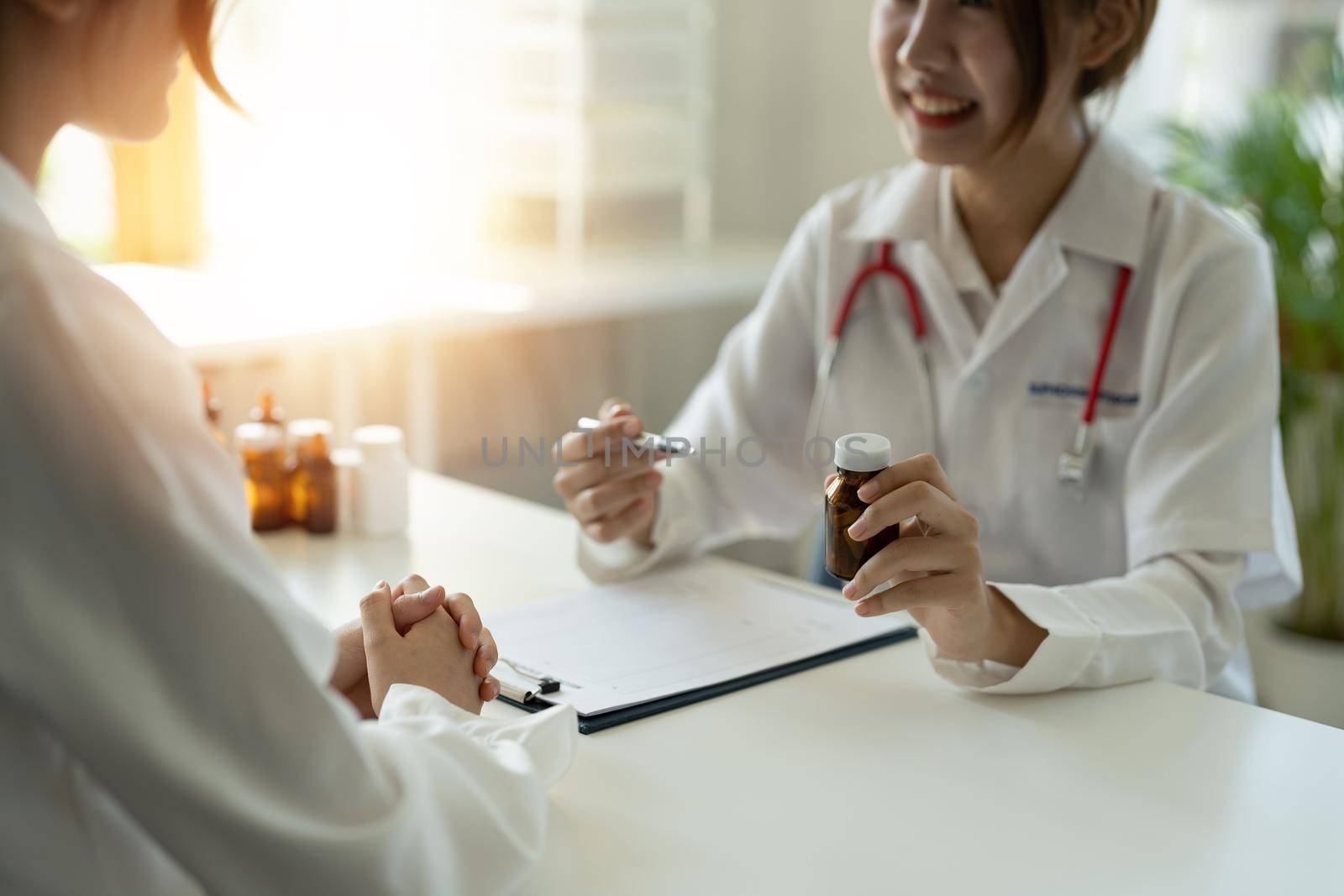 Female doctor giving pills bottle to patient in clinic. Concept of healthcare, medical treatment and insurance.