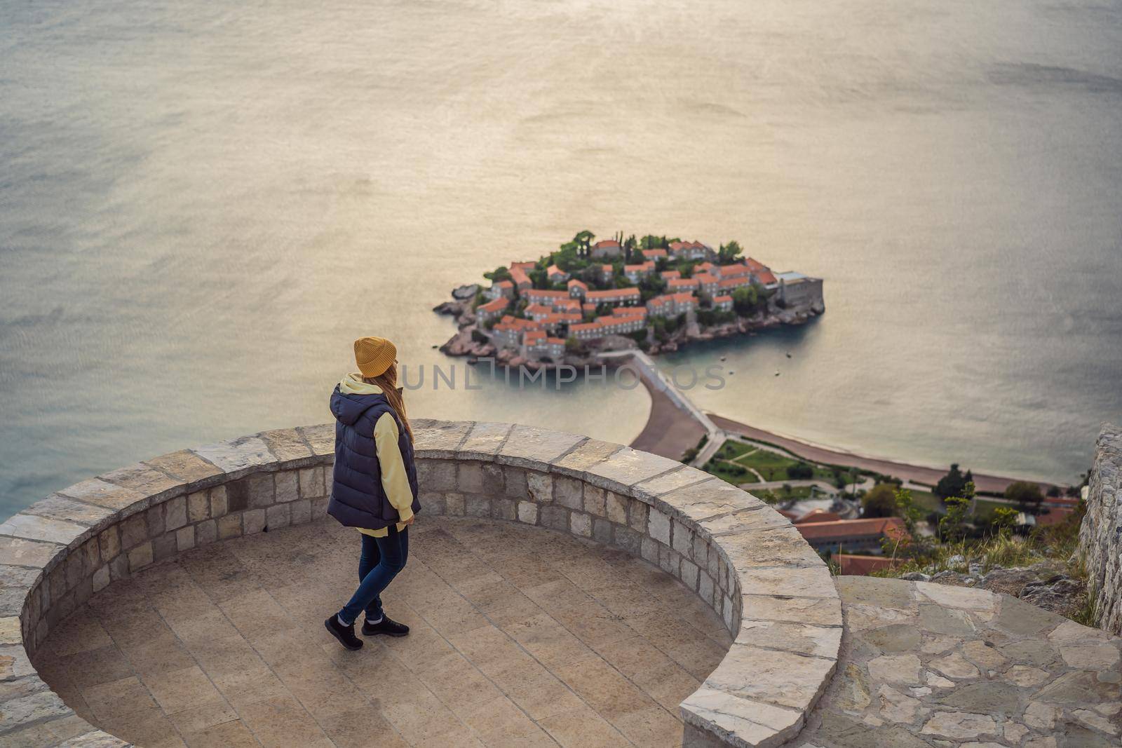 Woman tourist on background of beautiful view of the island of St. Stephen, Sveti Stefan on the Budva Riviera, Budva, Montenegro. Travel to Montenegro concept.