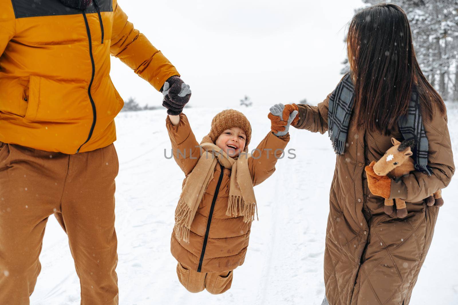 Happy family having a walk in winter outdoors in snow by Fabrikasimf