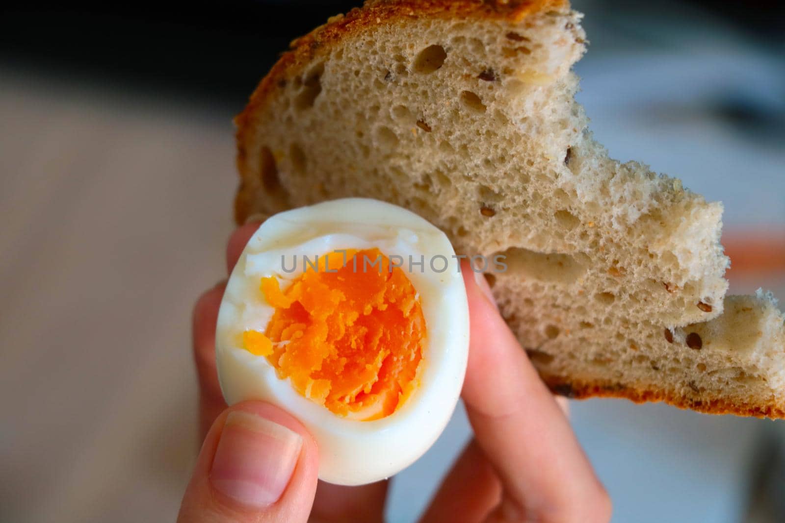 The girl holds in her hand a boiled egg and bread. A quick snack