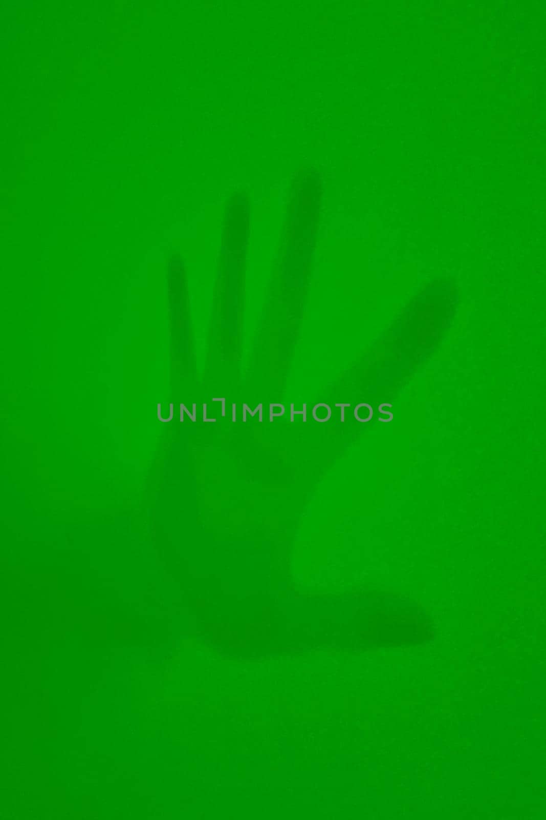 On a green background, the shadow of a man's hand