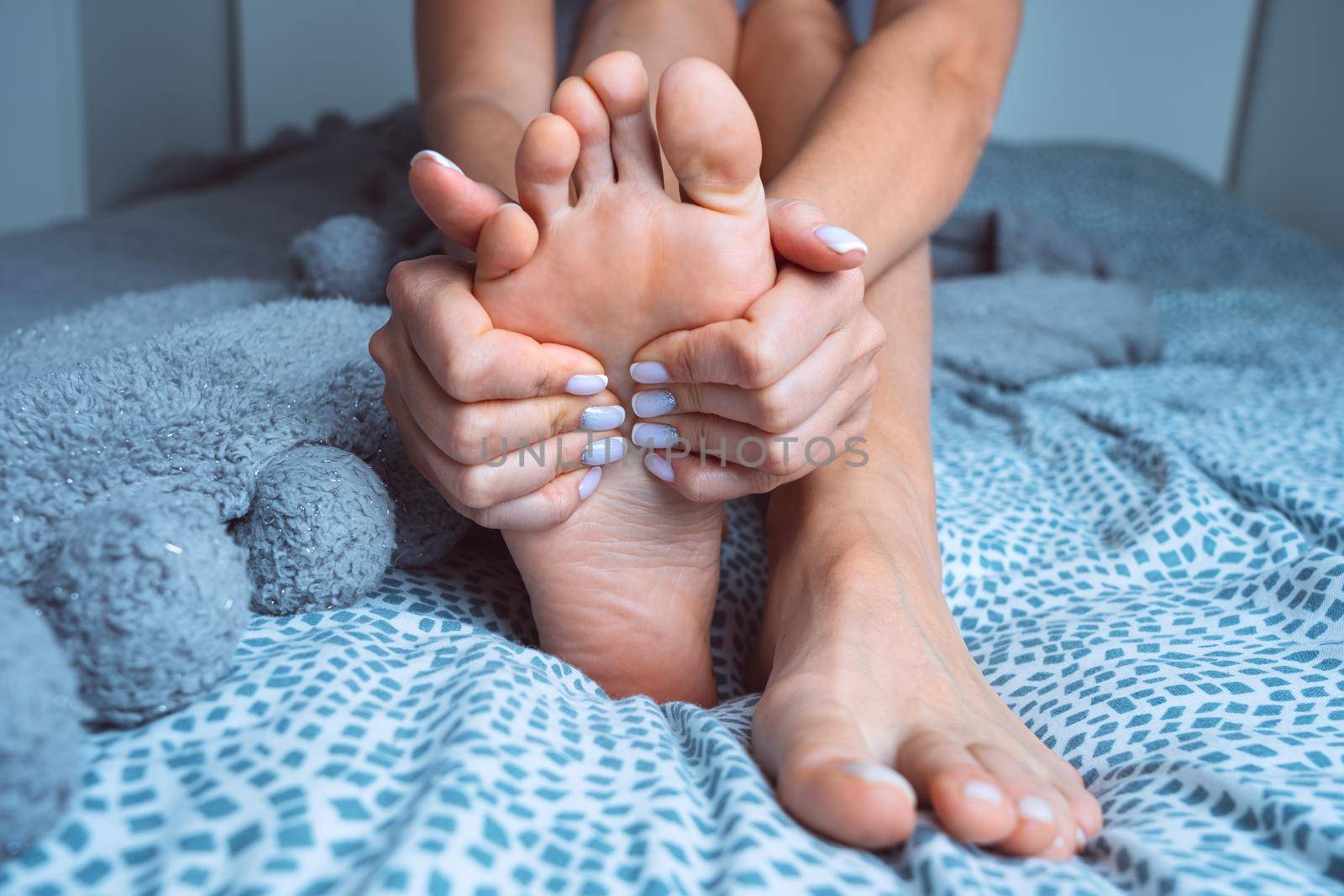 Woman suffering from feet pain or feet ache and massaging painful foot. Leg cramps, pain in legs or muscle spasm by DariaKulkova