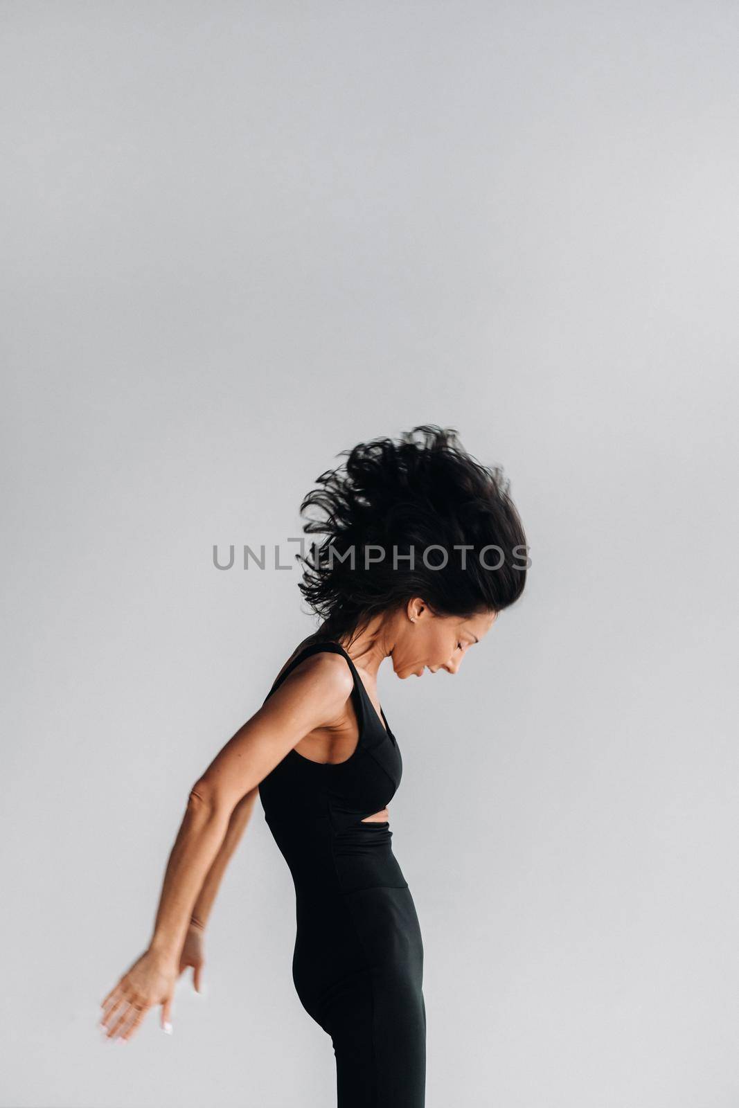 A woman in black sportswear is engaged in dynamic kali meditation in the Yoga hall.