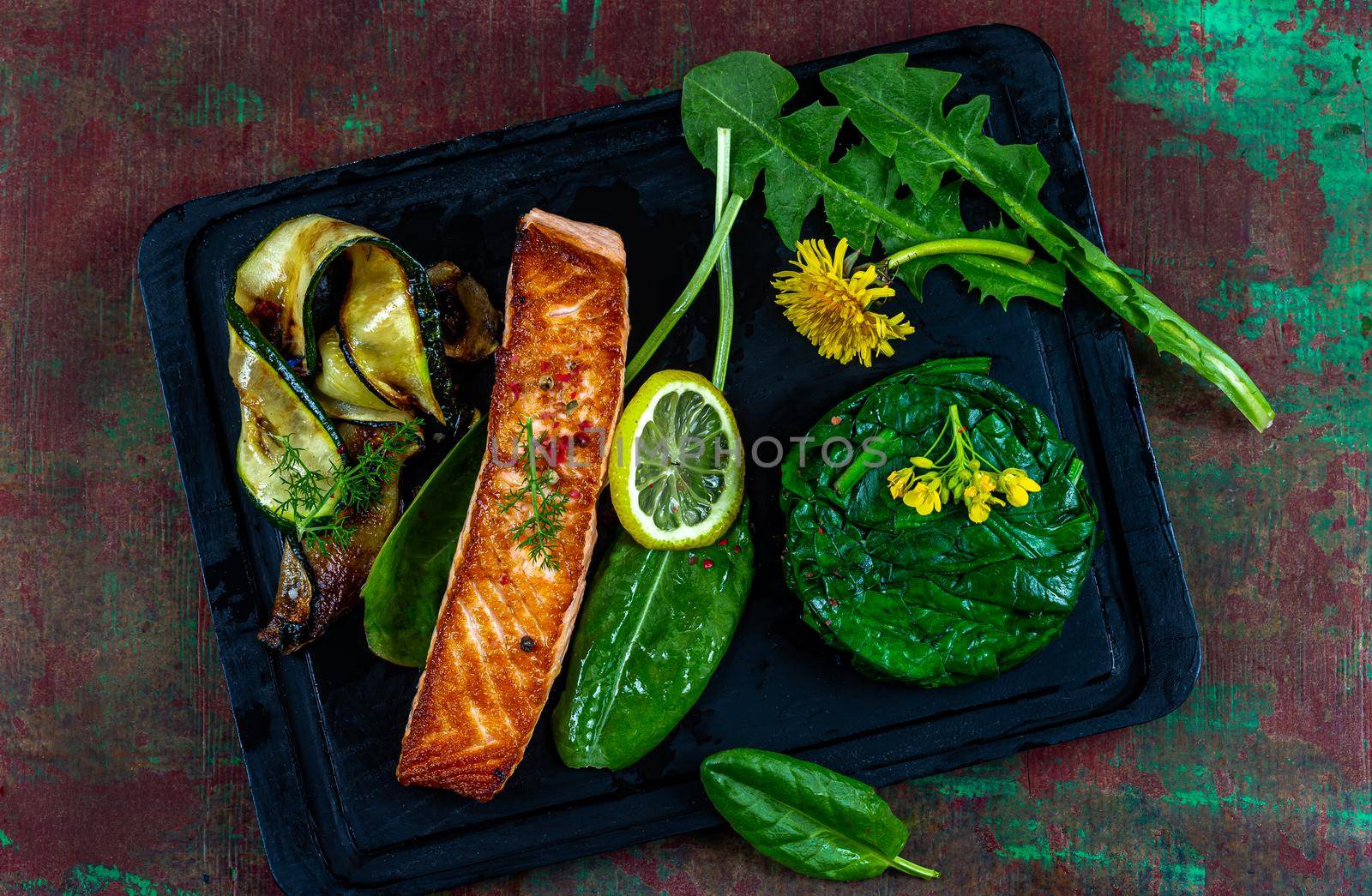 Salmon steak accompanied by vegetables on black wooden plate by JPC-PROD