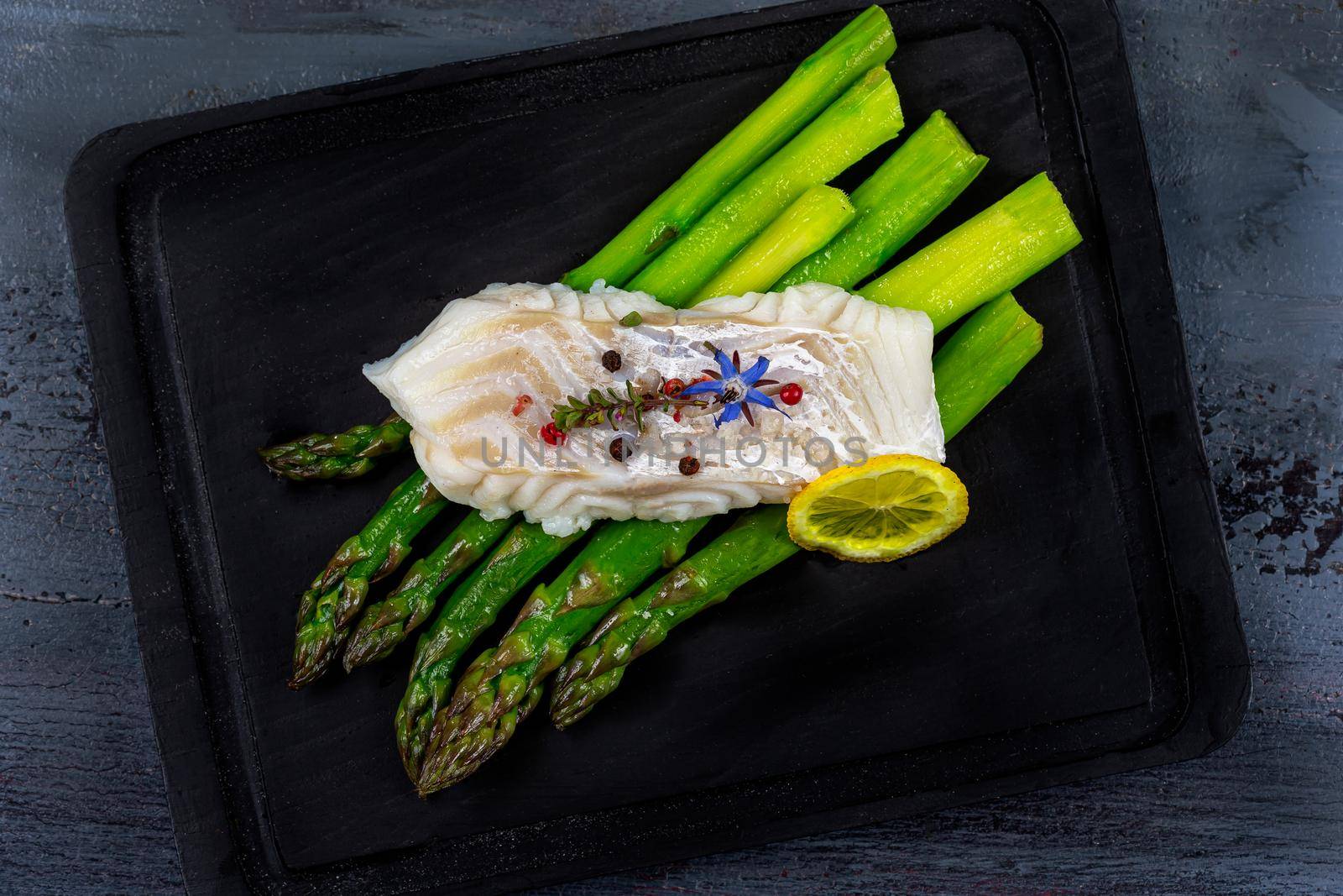Cod pavement placed on green asparagus, seen from above.