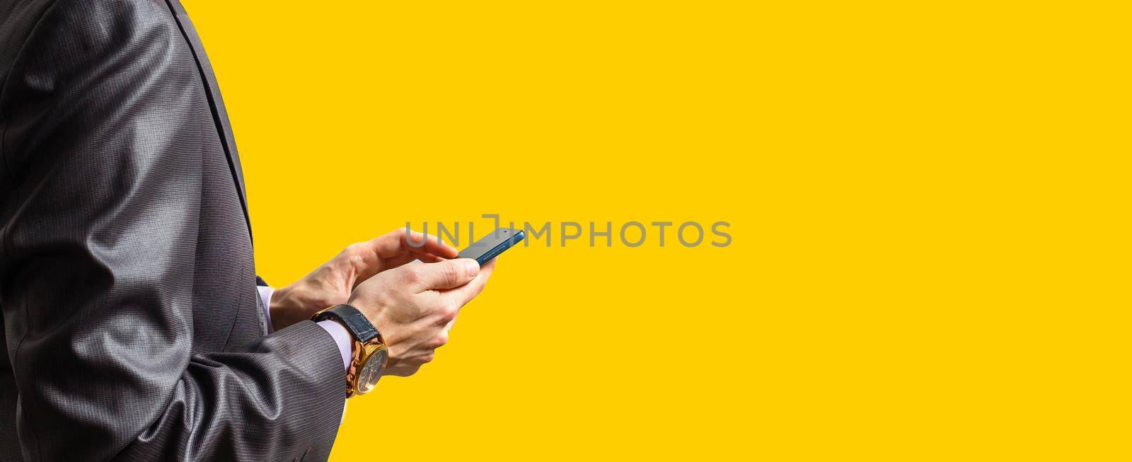 Hands of businessman calling by phone yellow background