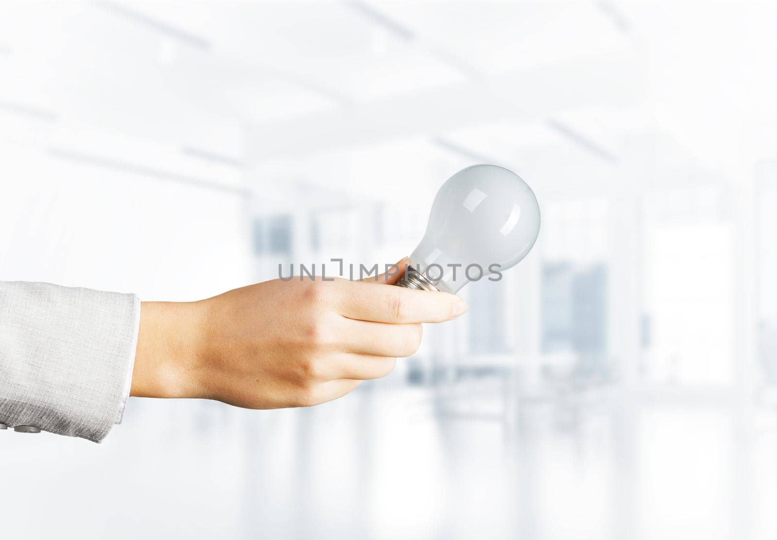 Human hand with incandescent lamp on blurred office background. Professional business assistance and consulting service. Successful solution business motivation with electric light bulb.