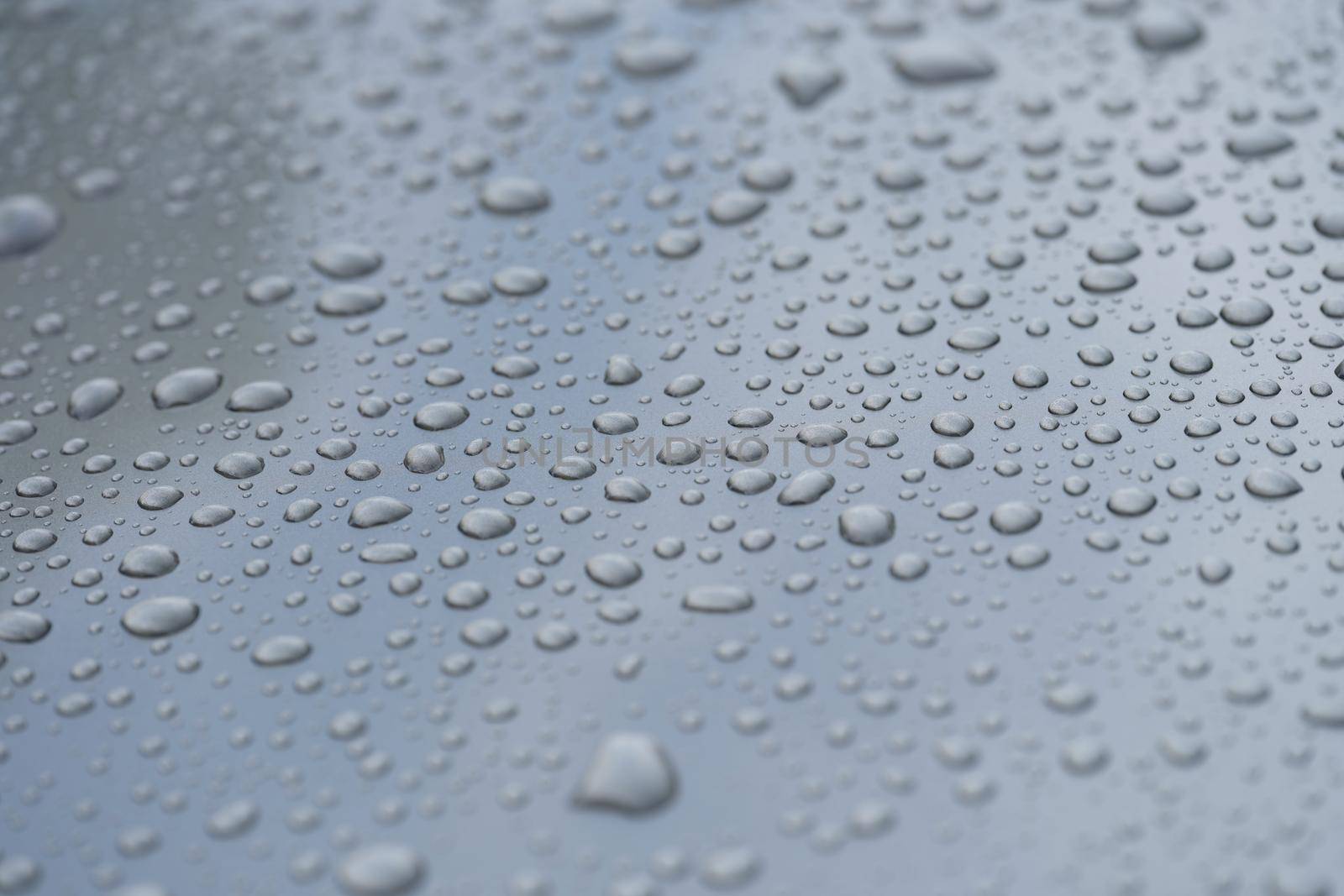 Raindrops on black hood of car. Rain on glass concept